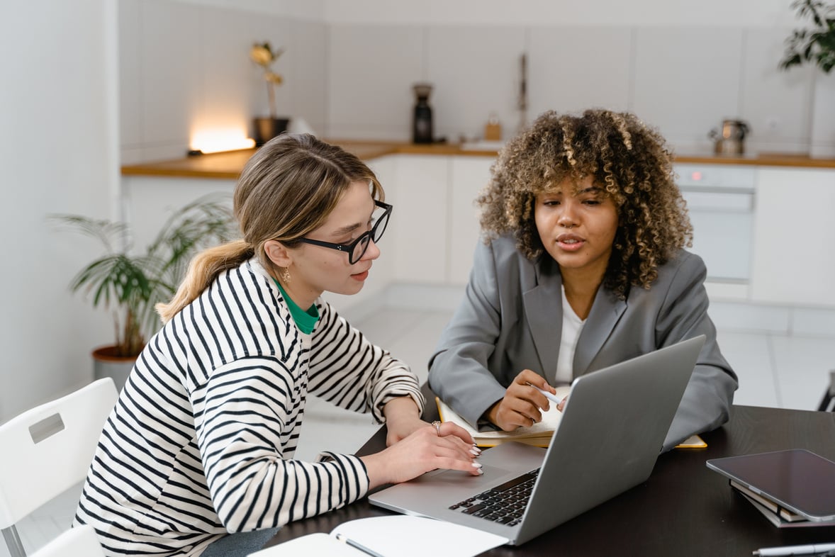 Woman in Stripe Shirt Using an Ipad Beside the Woman with Gray Coat